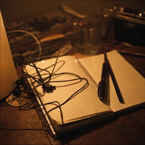An open notebook with headphones and pens